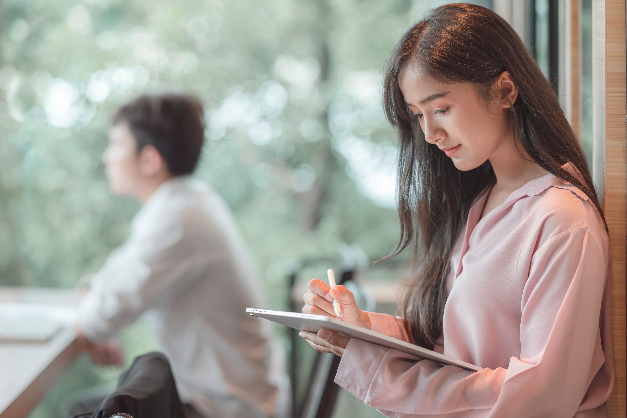 Assistant writing on tablet with digital pen during a business meeting