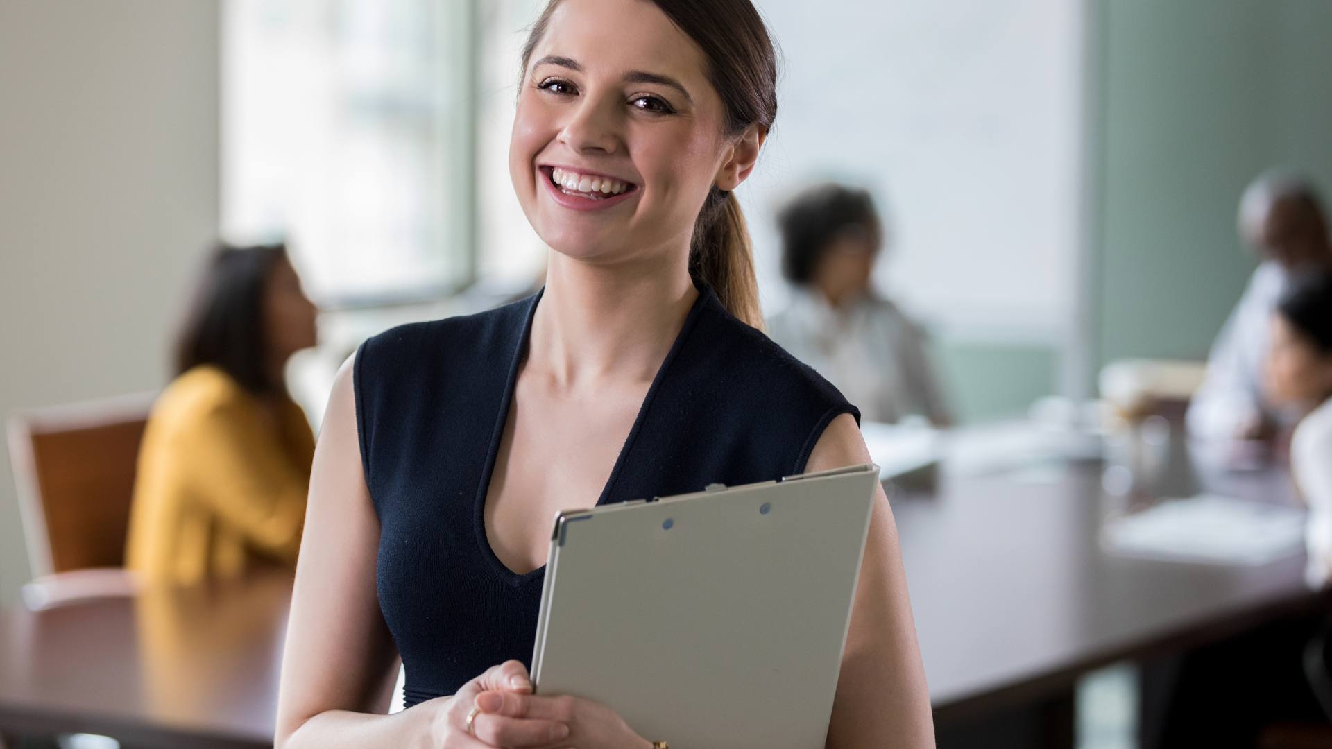 An administrative assistant proudly smiling at work. She is feeling confident about her career, knowing which administrative assistant certification course to choose.