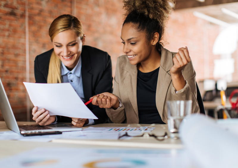 Two female coworkers pointing to and discussing a document
