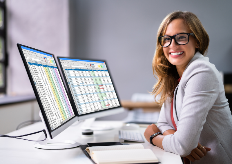 Female professional seated at computer with spreadsheets on screen