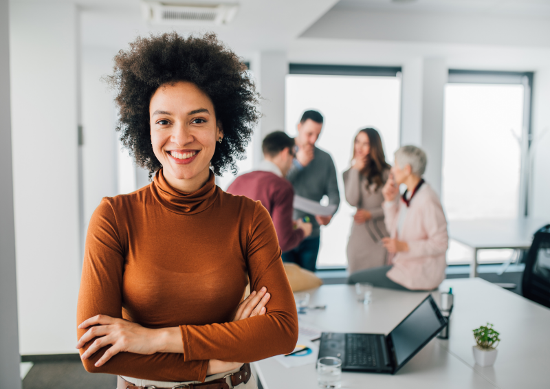 Businesswoman smiling at camera with group of colleagues behind her