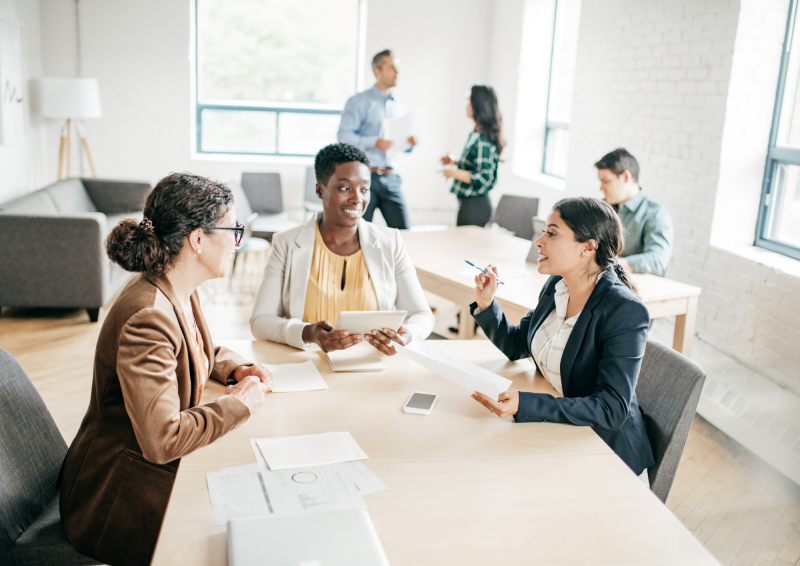 three female coworkers chatting around a table