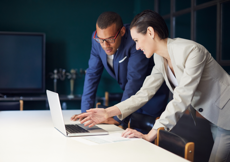 professional women encouraging man to her right to look at laptop