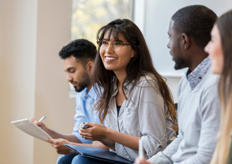 A woman smiles while looking to the left, surrounded by her coworkers