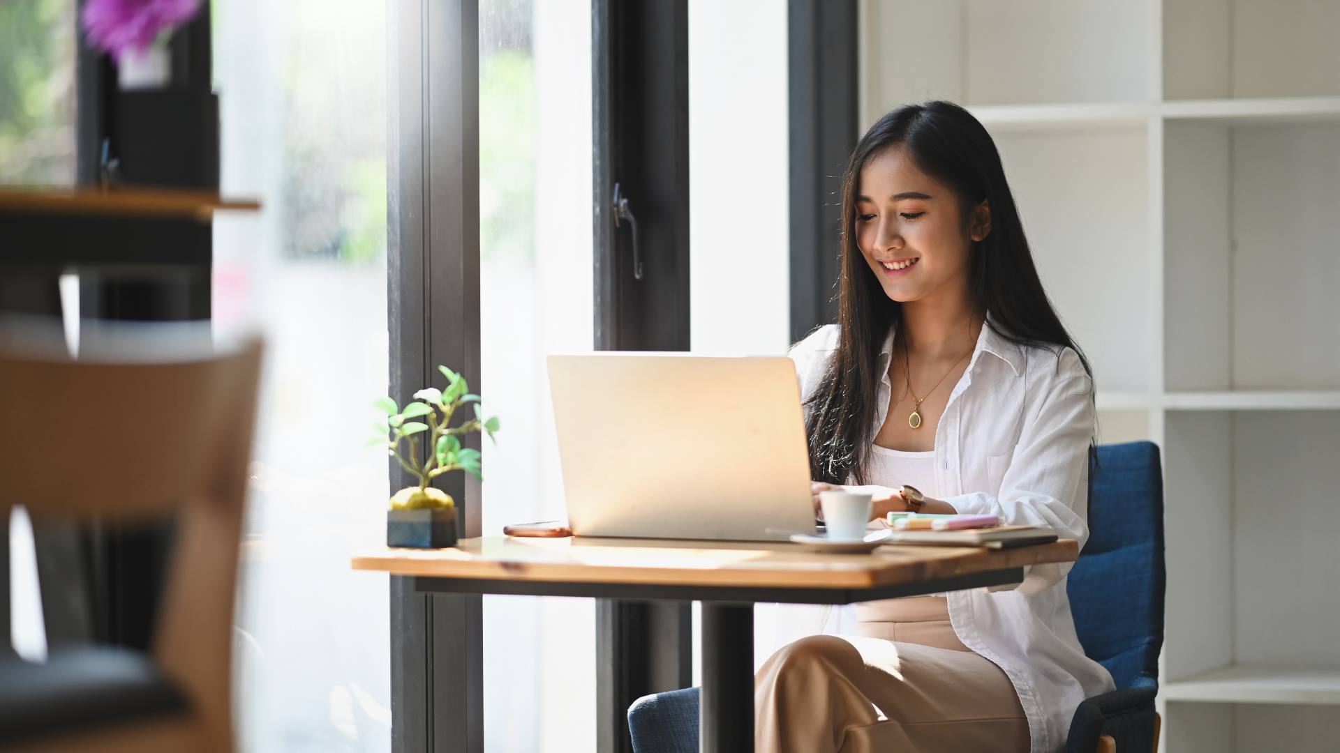 Executive assisting can be challenging at times. This executive assistant is smiling at her desk in front of her laptop. She's made her job seamless thanks to additional tools and technology.