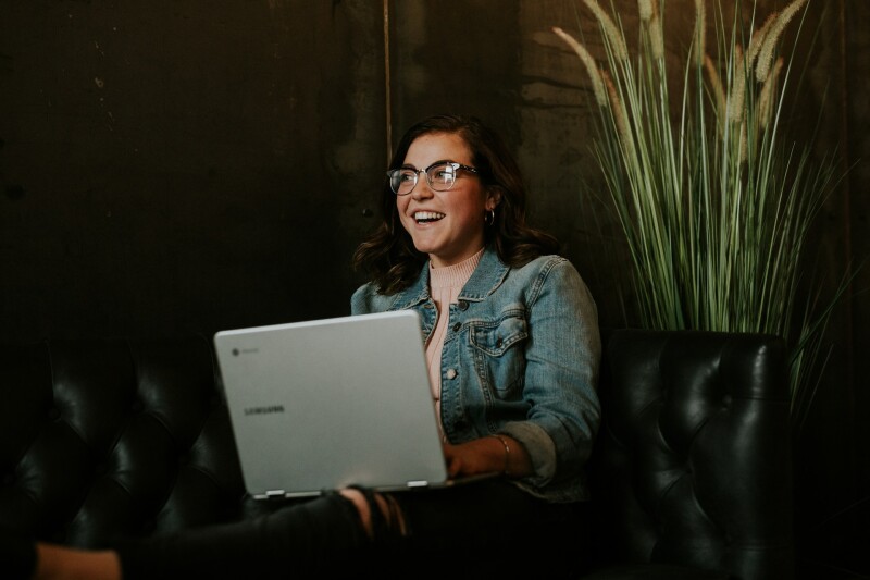 woman with glasses on laptop smiling