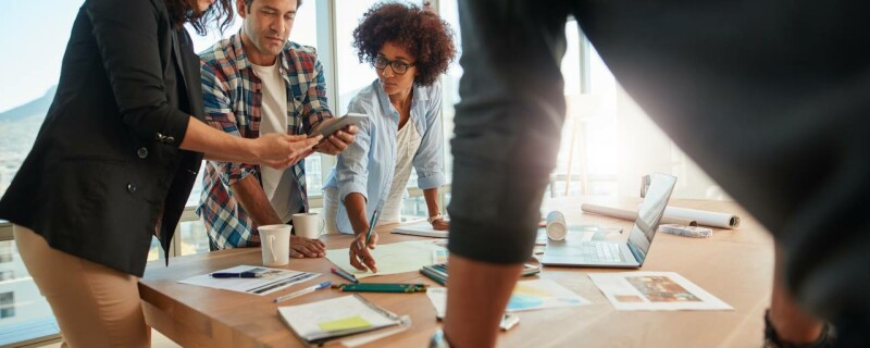A team of coworkers working at a large desk with the project manager.