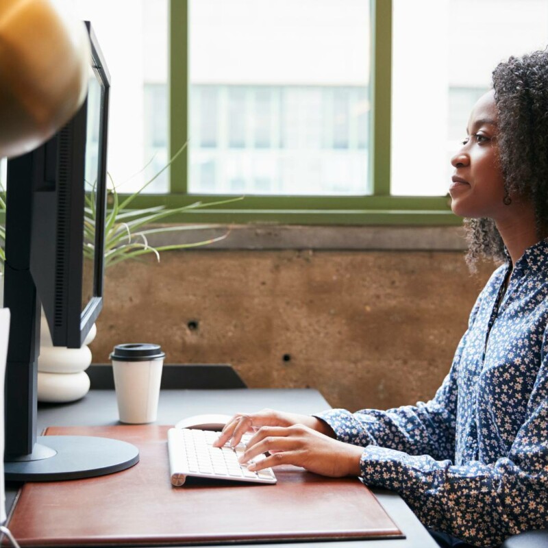 An administrative assistant sits at her desk and uses AI prompts to streamline her daily tasks.