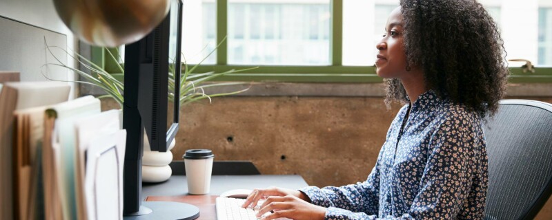 An administrative assistant sits at her desk and uses AI prompts to streamline her daily tasks.