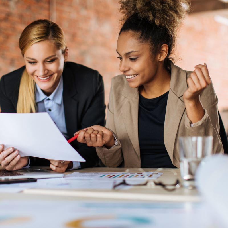 Two female coworkers pointing to and discussing a document