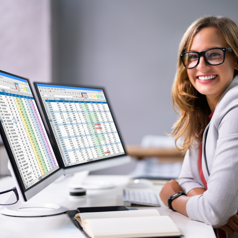 Female professional seated at computer with spreadsheets on screen