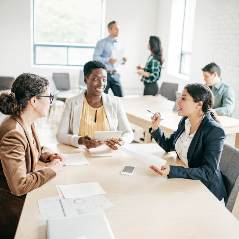 three female coworkers chatting around a table