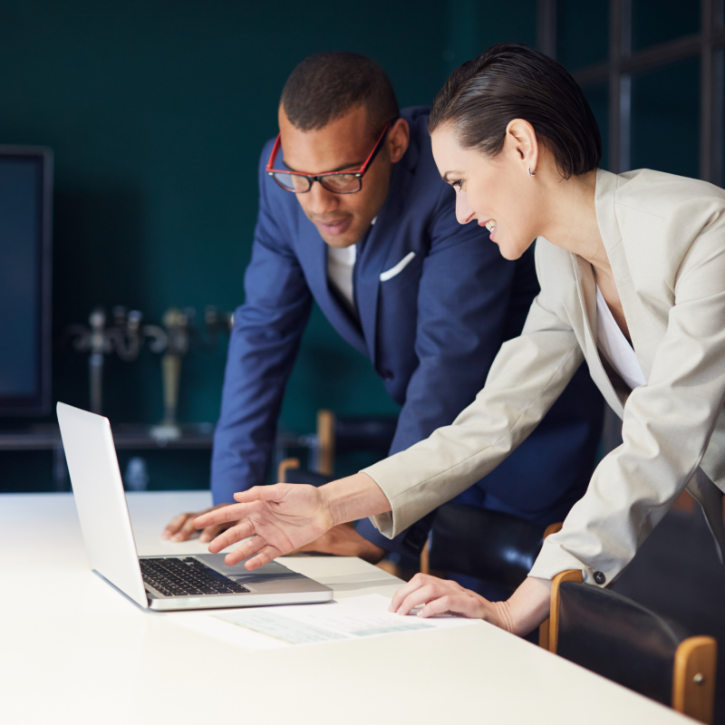 professional women encouraging man to her right to look at laptop