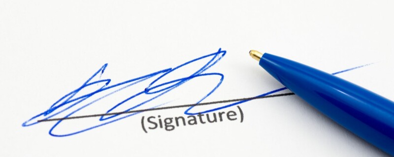 Someone signing their signature on a piece of paper