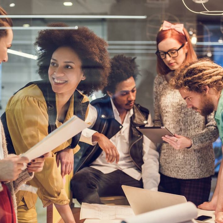 A group of coworkers in the workplace, including an administrative professional, all working on a project together.