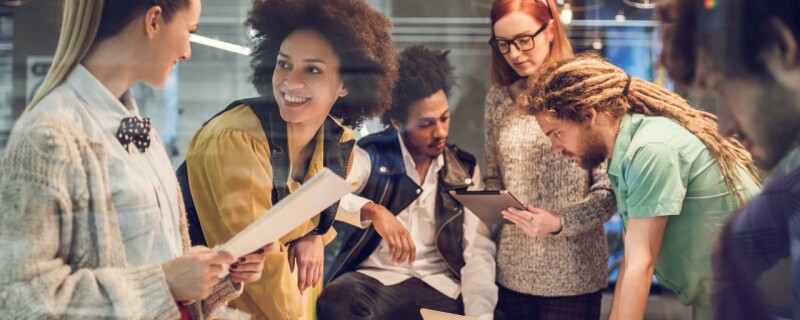 A group of coworkers in the workplace, including an administrative professional, all working on a project together.