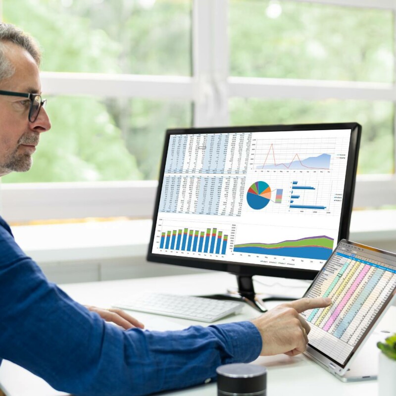 A man sits at his office desk and views organizational business KPIs.