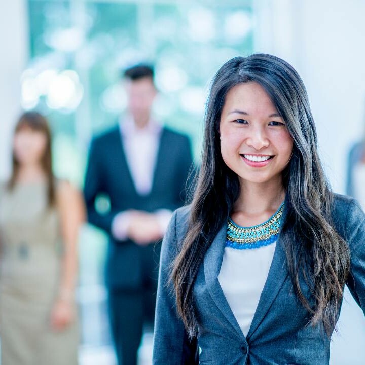 A sales leader standing in the forefront with her sales team faded in the background.