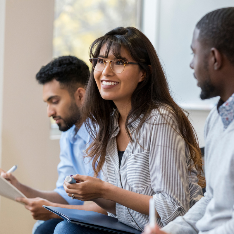 A woman smiles while looking to the left, surrounded by her coworkers