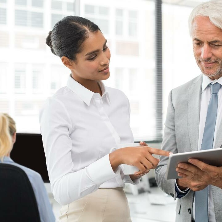 A Senior Executive Assistant discussing Office Manager roles with her boss while looking at a tablet.