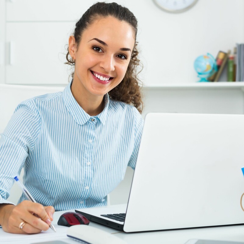 administrative assistant writing in front of laptop