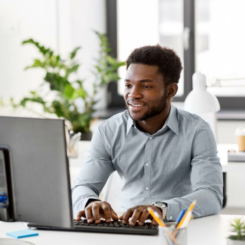 An administrative professional sitting at his desk on his computer, implementing AI tools at his job.