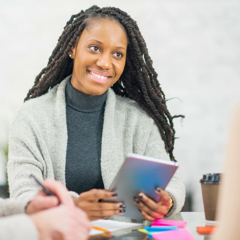 An administrative professional smiling with her coworkers. She is applying the Platinum Rule, and treating others with respect at her job.