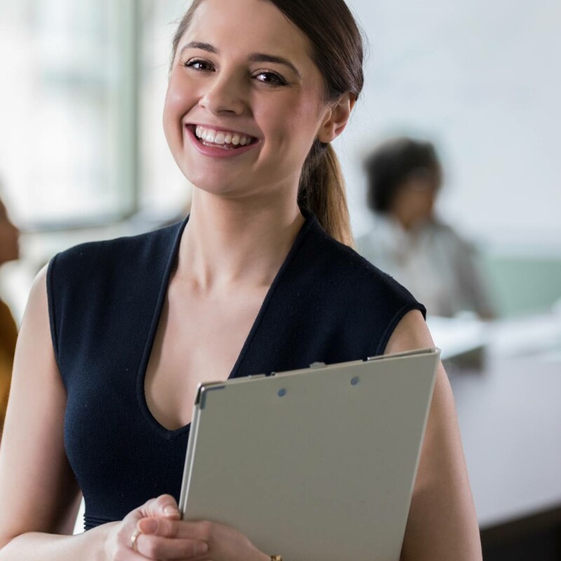 An administrative assistant proudly smiling at work. She is feeling confident about her career, knowing which administrative assistant certification course to choose.