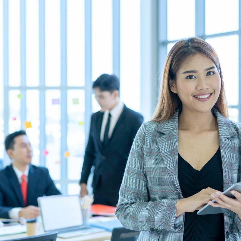 executive assistant using tablet while men stand behind her