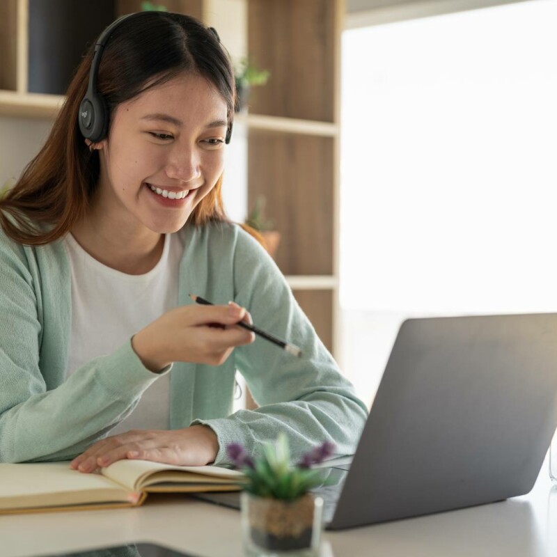 An administrative professional sitting at her laptop taking notes and interacting online, showing the importance of professional training programs.