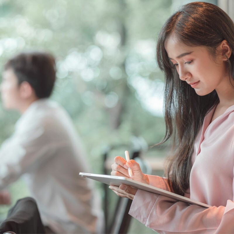 Assistant writing on tablet with digital pen during a business meeting