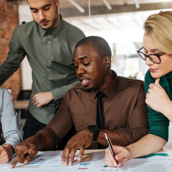 An admin professional showing their active listening skills while in a meeting with four of the coworkers.
