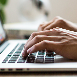 man typing on laptop keyboard