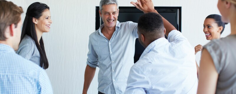 A manager congratulates his employees on a job well-done to boost employee morale.