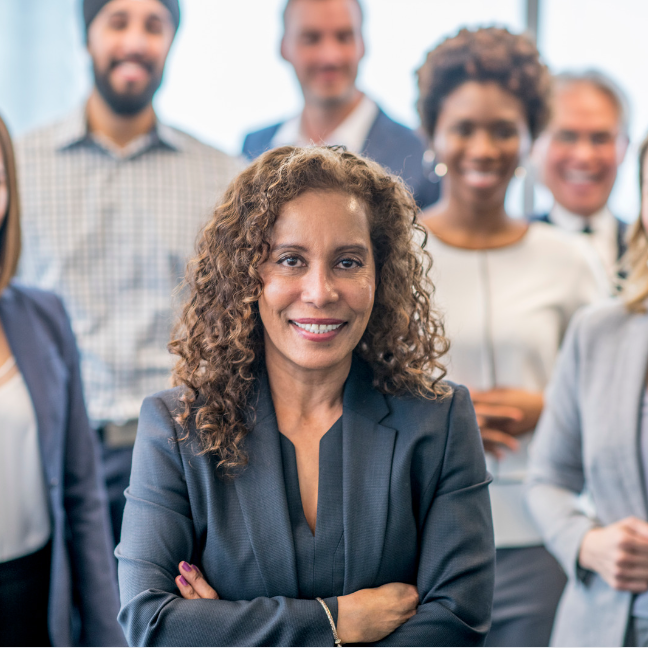 A group of diverse employees surround a female leader, who has her arms crossed