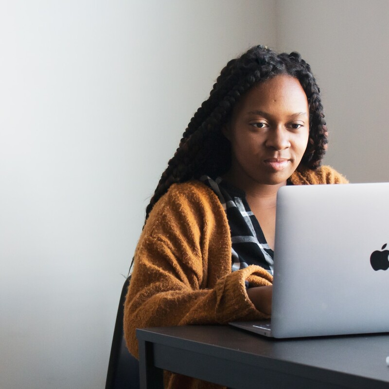 woman on laptop in orange sweater