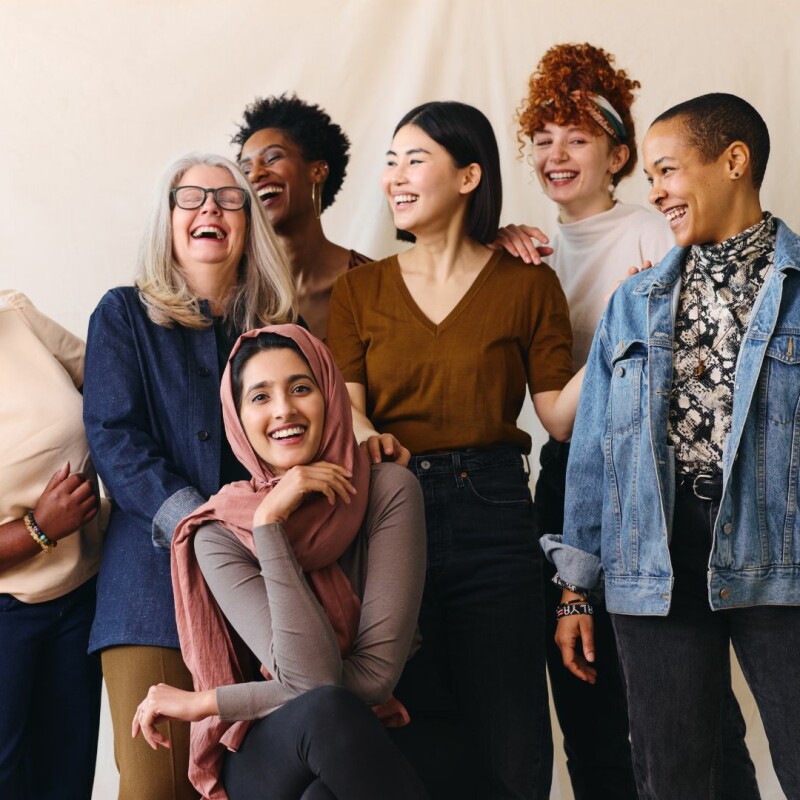 A group of women of different ages, races, and cultures stand together, smiling and encouraging one another. Image demonstrates the power of diversity, equity, and inclusion