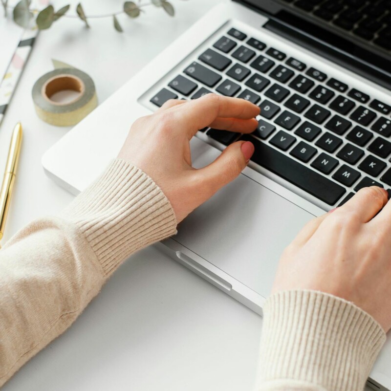 A woman sits at her desk, typing on her computer. Image demonstrates the importance of learning how to become a better writer for your job.