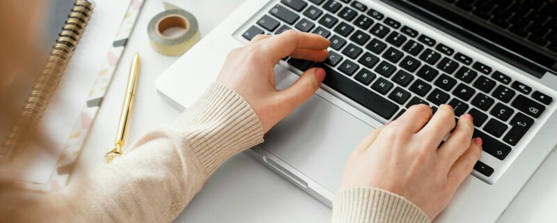 A woman sits at her desk, typing on her computer. Image demonstrates the importance of learning how to become a better writer for your job.