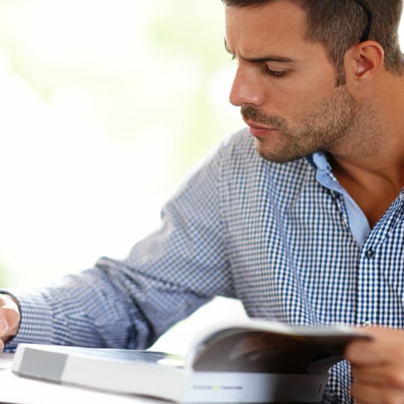 A man sits poring over a book and his notes, working hard. Image demonstrates the importance of learning how to set goals.