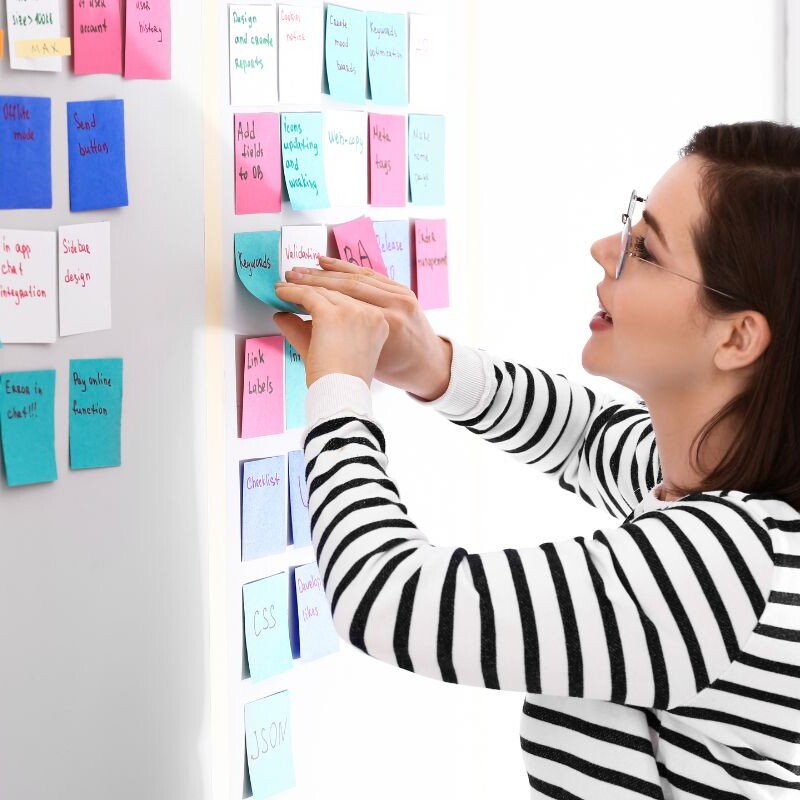Operations manager strategizing and organizing tasks on a whiteboard using sticky notes for effective task management.