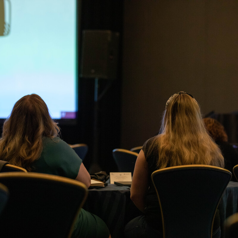 Two female attendees at EA Ignite Conference fall 2023, looking at a screen