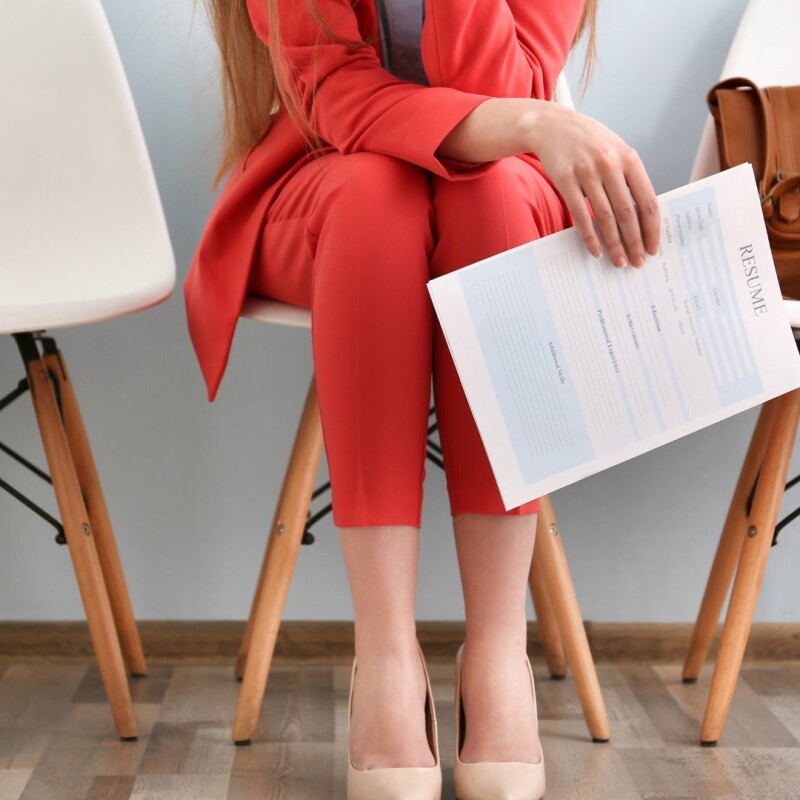 A woman sits nervously, clutching her resume, before an interview.