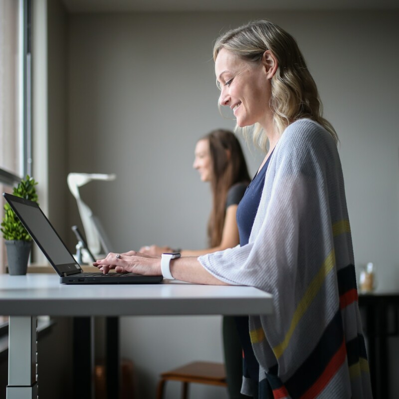 woman smiling and typing at standing desk