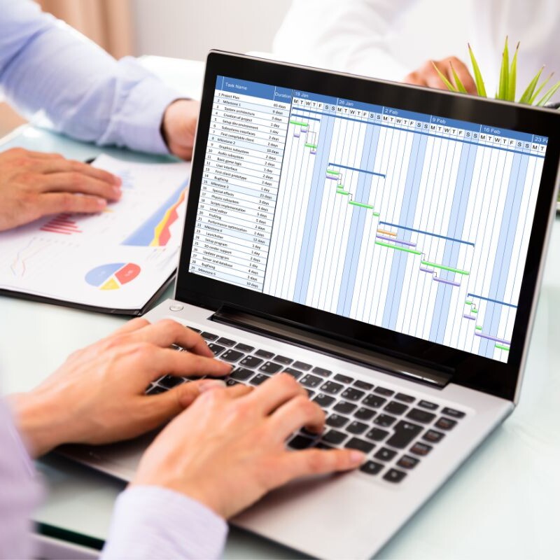 An operations manager sits at a computer, displaying a neatly organized project schedule.