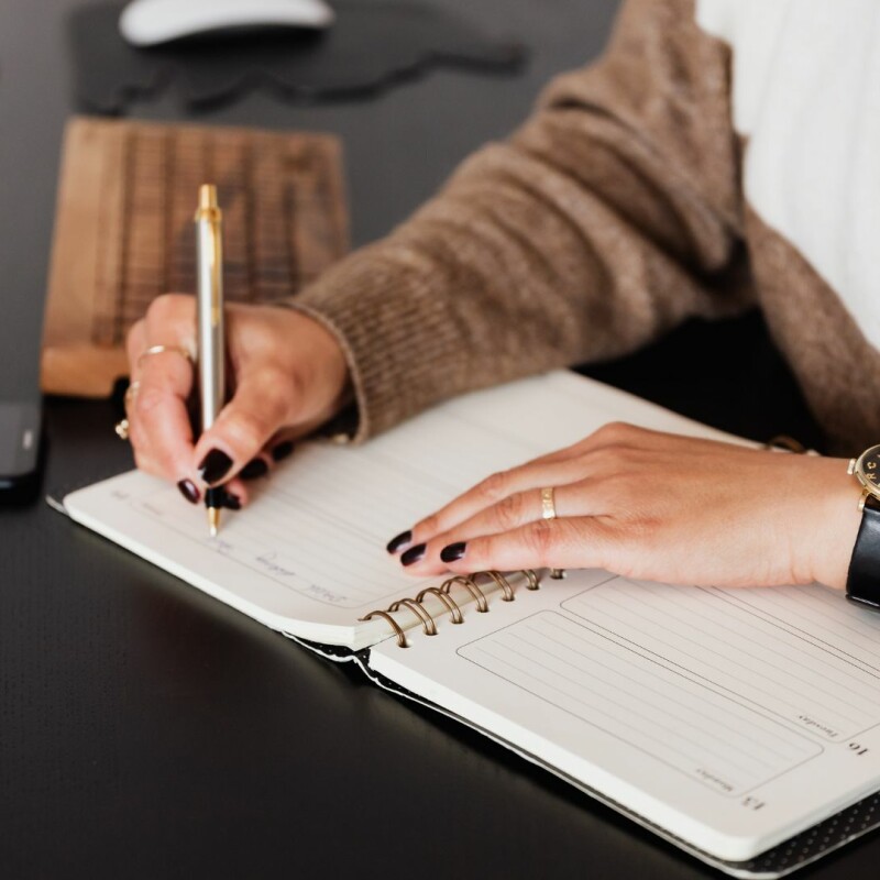 A woman sits at her desk, taking notes by hands.
