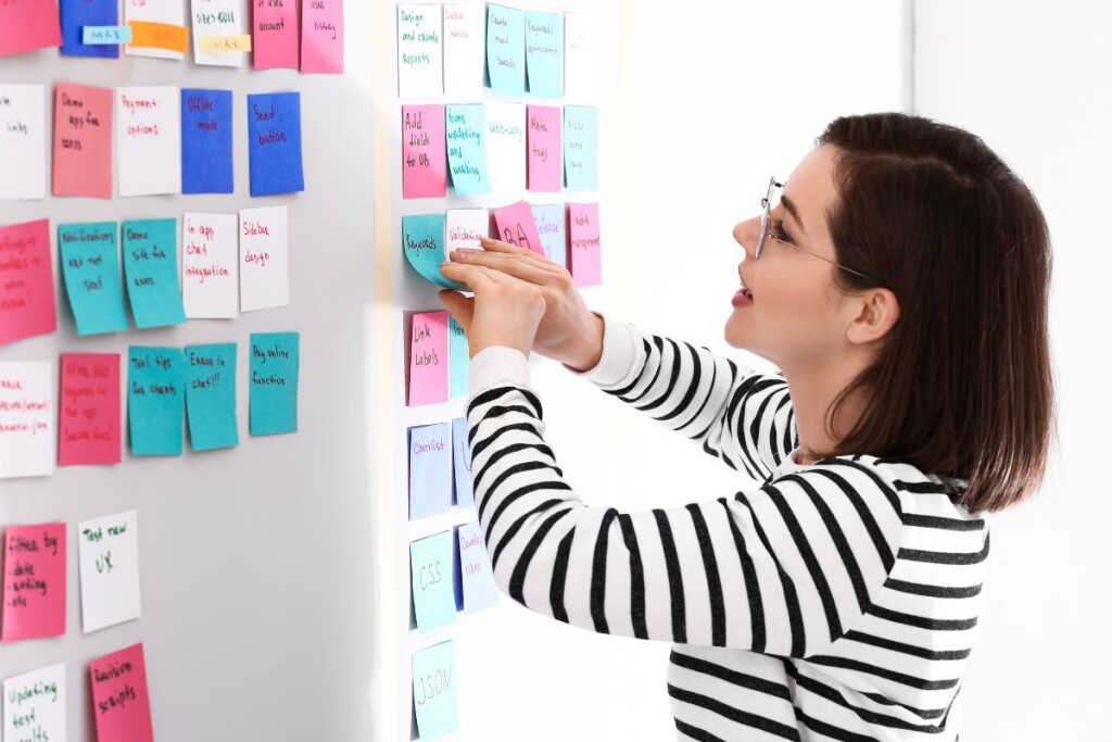 Operations manager strategizing and organizing tasks on a whiteboard using sticky notes for effective task management.