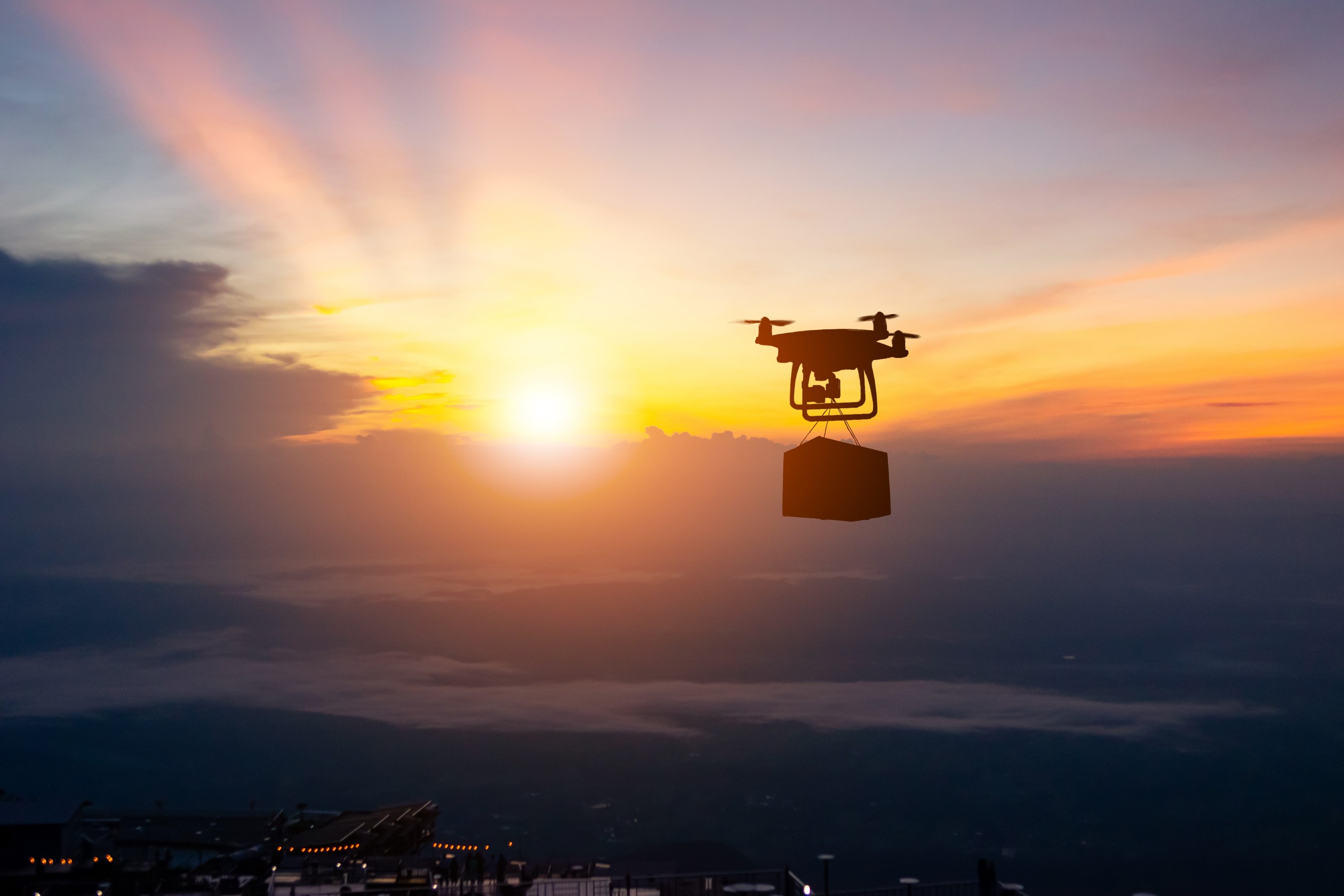 Delivery drone flying in front of a sunset
