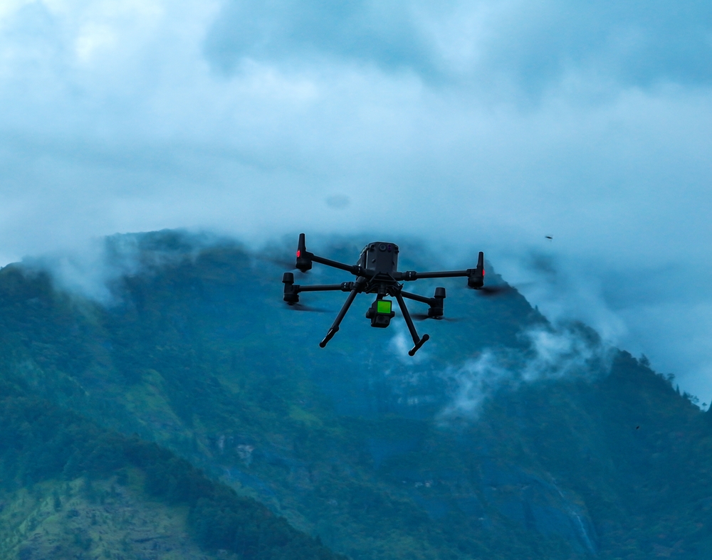Industrial drone flying through mountains with Lidar sensor payload for aerial surveyor aerial mapping.
