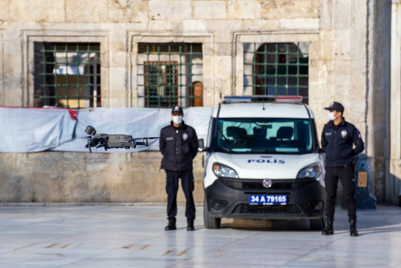 Police Officers standing next to van with drone flying in front of them